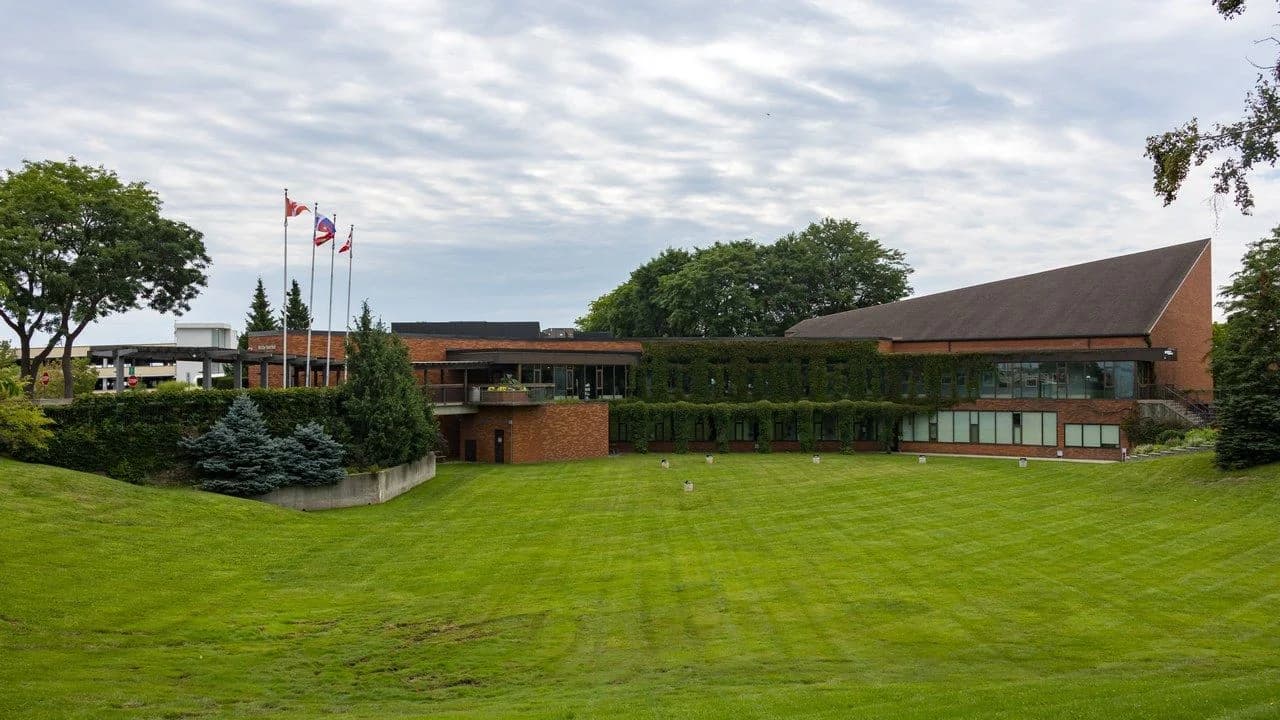 Daytime exterior of Whitby Town Hall on Rossland Road in Whitby, Ontario, with flags; no people visible.