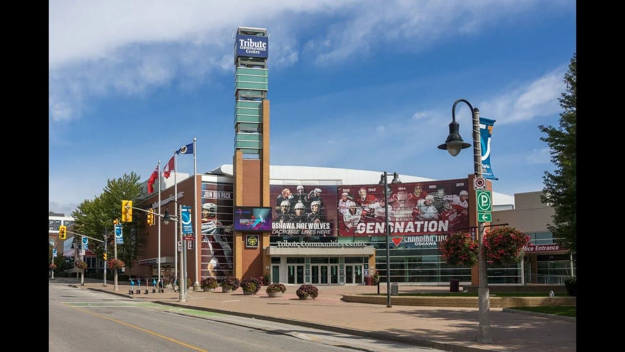 Exterior of the Tribute Communities Centre, home arena of the Oshawa Generals, on Athol Street in downtown Oshawa; arena facade carries team mural wraps; no people visible