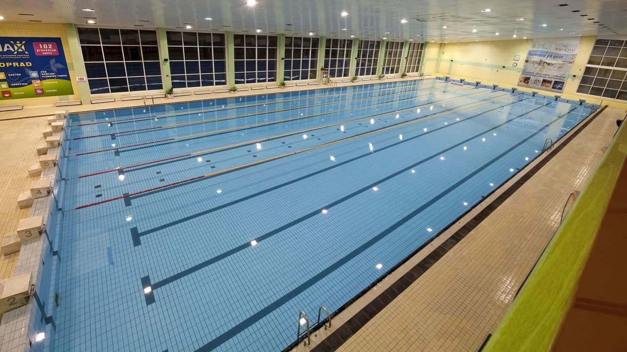 Empty 50-metre indoor swimming pool with lane markings; no people visible.