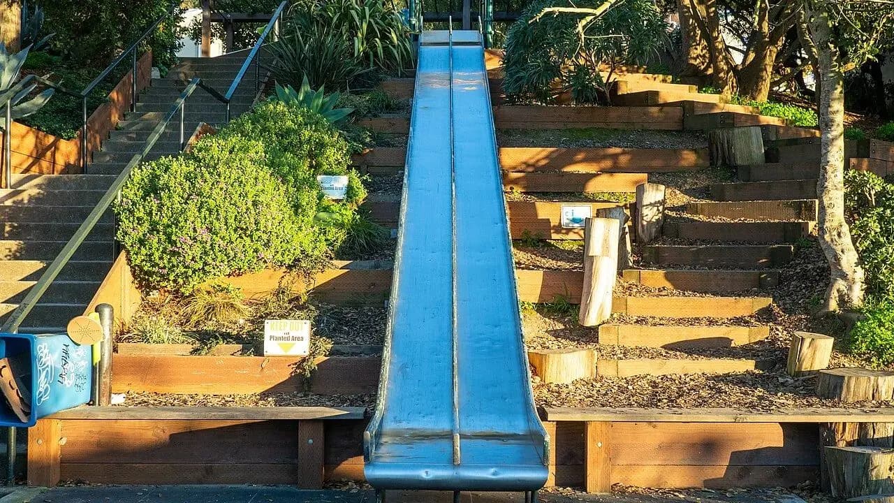 A playground slide with stairs in a park; no people present
