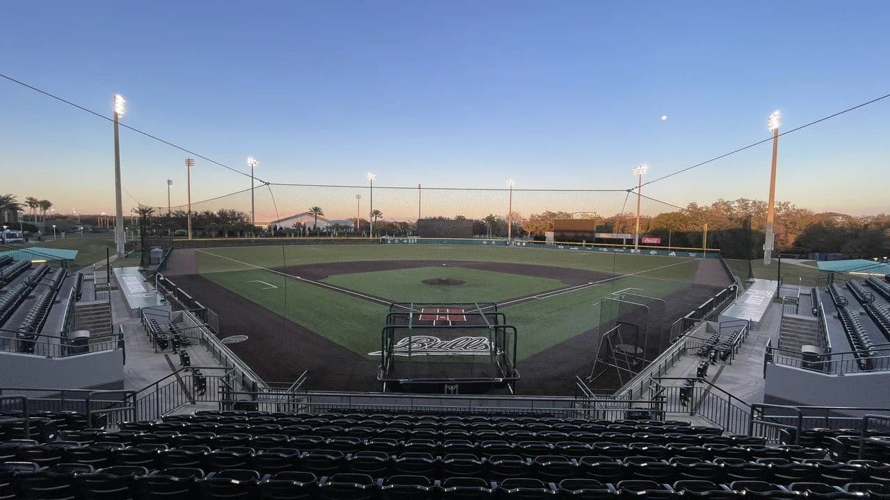 Empty baseball stadium at dawn with the diamond, pitcher's mound and empty stands; no people visible.